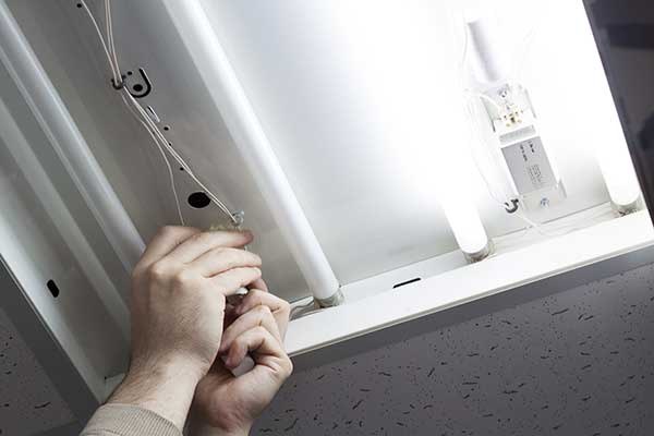 Close up of a worker fixing and replacing a faulty fluorescent light
